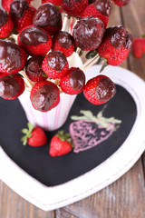 Strawberry in chocolate on skewers in cup on table close-up