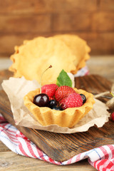 Tasty tartlets with berries on wooden table