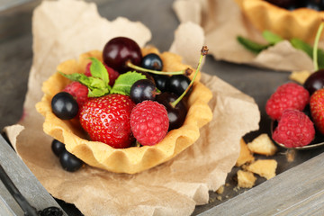 Tasty tartlets with berries on wooden tray