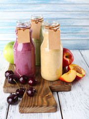 Bottles of delicious smoothie on table, close-up
