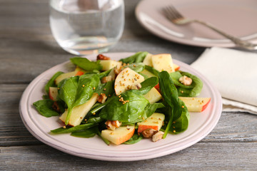 Green salad with apples, walnuts and cheese on wooden