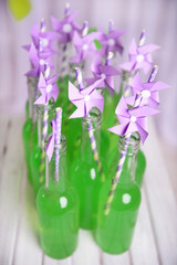 Bottles of drink with straw on table on decorative background