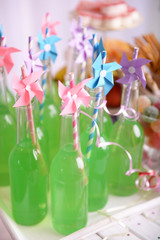 Bottles of drink with straw and sweets on decorative background
