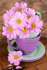 Cups and saucers with flowers on wooden background