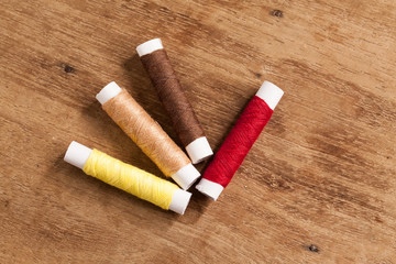 wood Background with sewing tools and colored thread.