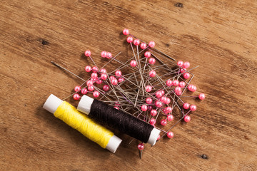 wood Background with sewing tools and colored thread.