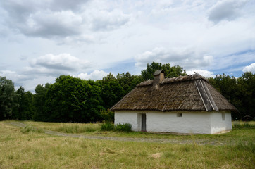 Fototapeta na wymiar Antique white clay house with hay roof in Pirogovo park, Kiev
