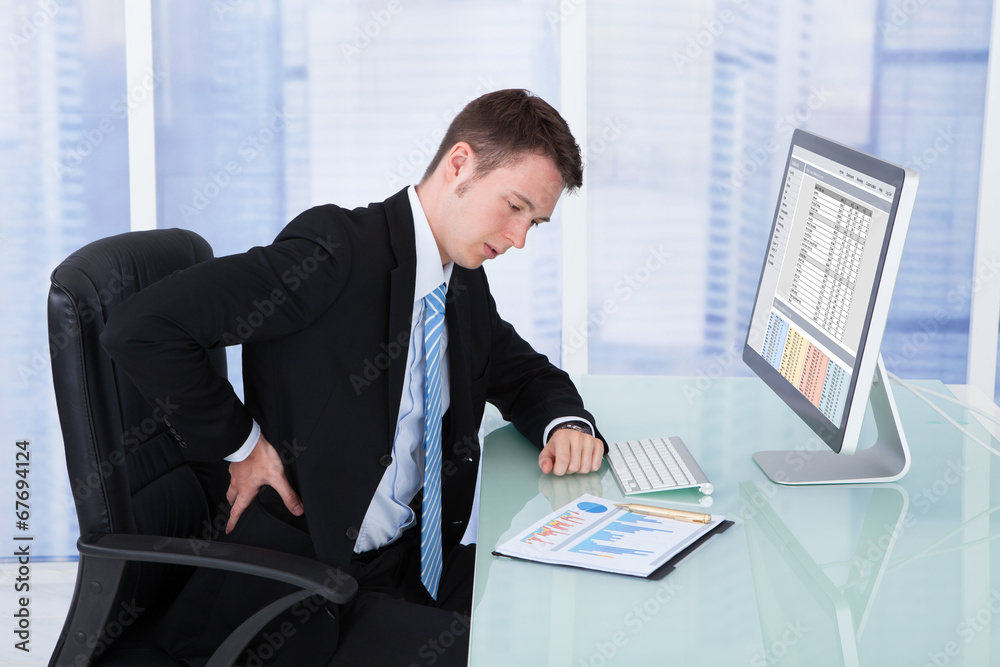 Poster businessman suffering from backache at computer desk