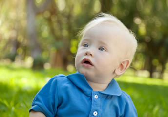 funny little boy sitting on the grass in the park