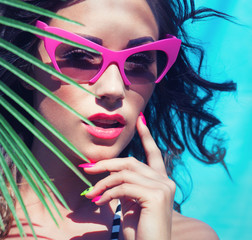 Young attractive woman wearing sunglasses under a palm tree