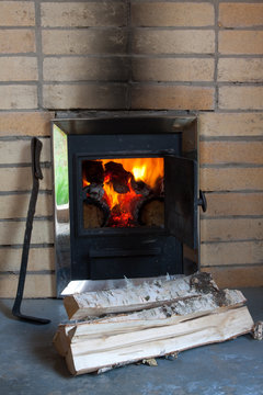 The wood stove with firewood and poker