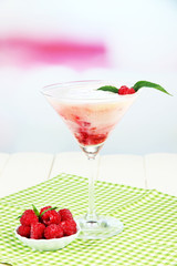 Raspberry milk dessert in cocktail glass, on light background