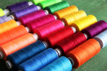 Multicolor sewing threads on wooden background