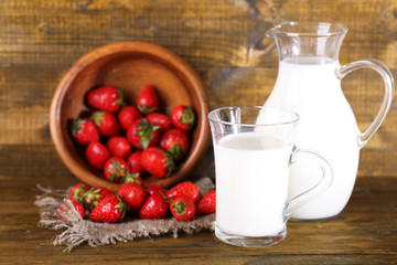 Ripe sweet strawberries in wooden bowl and jug with milk
