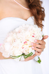 Bride holding wedding bouquet of white peonies, close-up,