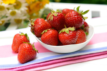 Ripe sweet strawberries in bowl on table in garden