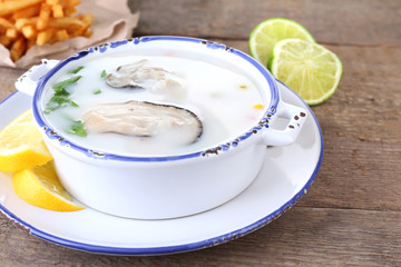 Tasty soup with oysters on wooden table