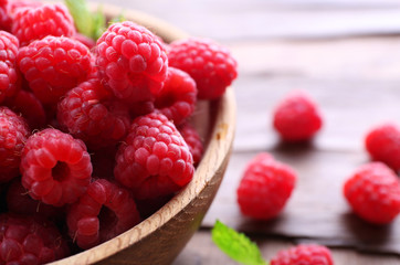 Ripe sweet raspberries in bowl on table close-up