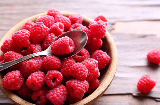 Ripe sweet raspberries in bowl on table close-up
