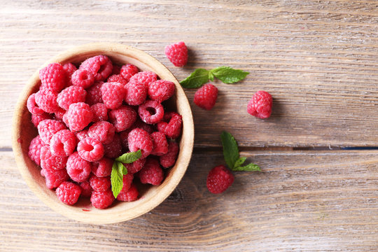 Ripe sweet raspberries in bowl on table close-up