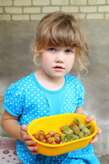 Little girl holding bowl with hazelnuts