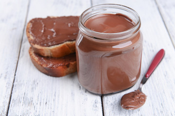 Sweet chocolate cream in jar on table close-up