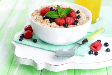 Tasty oatmeal with berries on table close-up