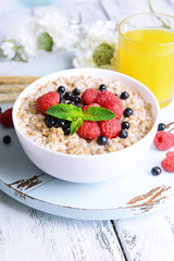 Tasty oatmeal with berries on table close-up