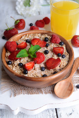 Tasty oatmeal with berries on table close-up