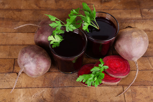 Glasses of fresh beet juice and vegetables on wooden background