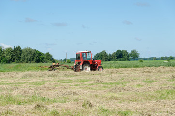 Obraz premium tractor machine equipment ted dry grass in field