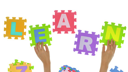 Hands forming word "Learn" with jigsaw puzzle pieces isolated