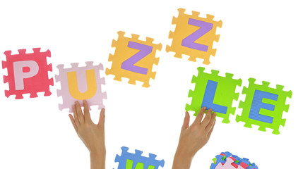 Hands forming word "Puzzle" with jigsaw puzzle pieces isolated