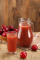 plum juice in a glass and pitcher, plums in a wicker basket on a