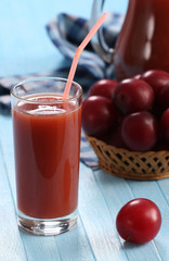 plum juice in a glass and pitcher, plums in a wicker basket