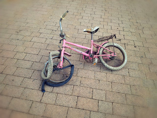 Broken pink bicycle lying on the street