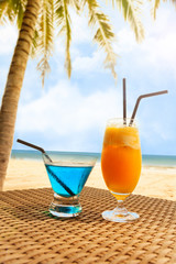 Two fresh cocktail on a beach under palm tree