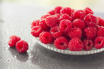 Raspberries in a bowl wet on wet background