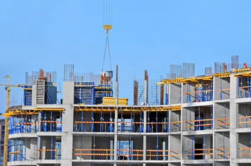 Crane lifting concrete mixer container against blue sky