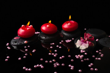 spa concept of red candles, zen stones with drops, orchid cambri