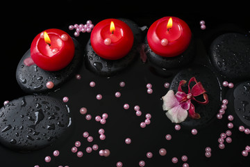 spa concept of red candles on zen stones with drops, orchid camb
