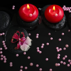 spa concept of red candles on zen stones with drops, orchid camb