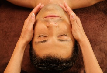 Handsome man having face massage in spa salon