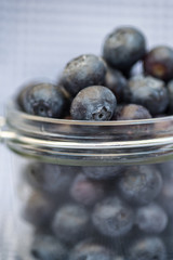 Fresh blueberries falling out of glass jar