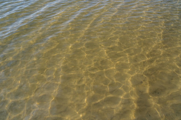 The sandy bottom of the river with the water ripples