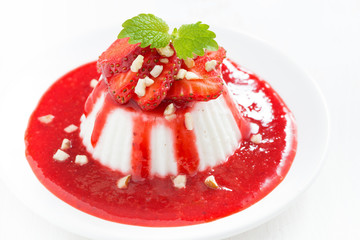 Vanilla panna cotta with strawberry sauce on a plate, top view