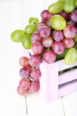 Ripe green and purple grapes in wooden box