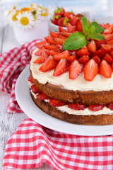 Delicious biscuit cake with strawberries on table close-up