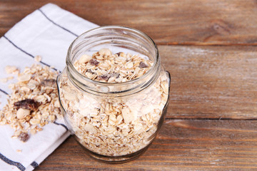 Homemade granola in glass jar, on color wooden background