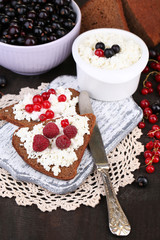 Bread with cottage cheese and berries on wooden board close-up